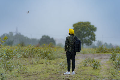 Young backpack man standing on field