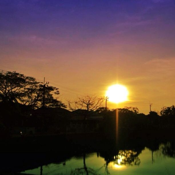 sunset, sun, silhouette, sky, tranquil scene, beauty in nature, scenics, tranquility, orange color, nature, sunlight, water, reflection, idyllic, lake, tree, plant, outdoors, sunbeam, no people