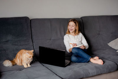Portrait of young woman using laptop while sitting on sofa at home
