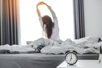 Midsection of woman relaxing on bed at home