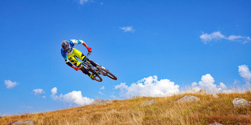 Low angle view of man jumping on field against sky