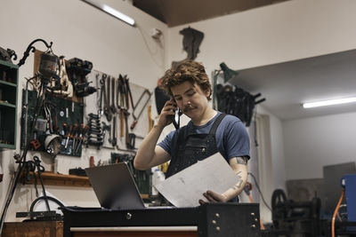 Blacksmith working with laptop and documents in his workshop