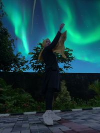 Full length of woman standing against aurora at night