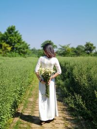 Rear view of woman standing on field against clear sky