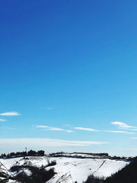 Scenic view of snow covered landscape against blue sky