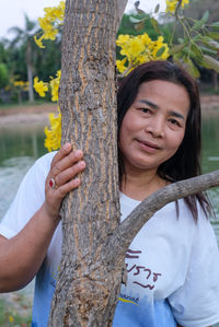 Portrait of man smiling against tree trunk