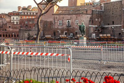 Street by fence against buildings in city