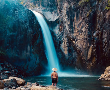 Rear view of man looking at waterfall