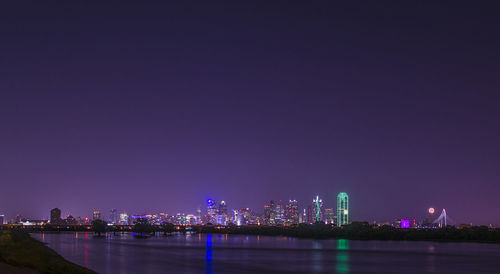 Illuminated cityscape against sky at night