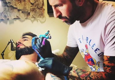 Artist making tattoo on shirtless man