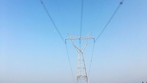 Low angle view of electricity pylon against clear blue sky