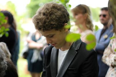 Young man looking down while standing in park