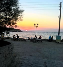 People on beach against sky during sunset