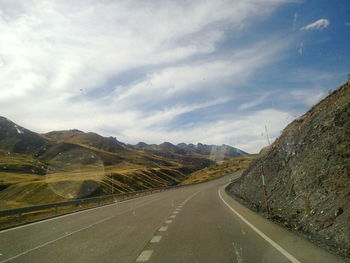 Road by mountains against sky