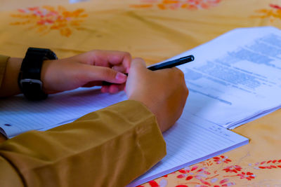 Midsection of woman reading book on table