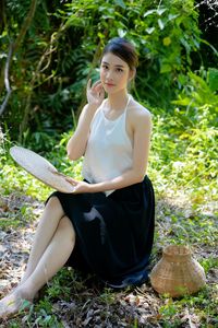 Side view of young woman sitting on field