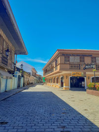 Street amidst buildings against blue sky