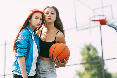 Portrait of two charming girls with a basketball on the sports field. friendship, best friends