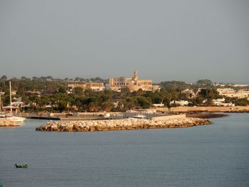 Buildings by sea against clear sky