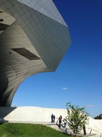 People in front of modern building against blue sky