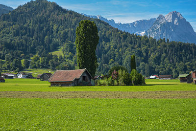 Scenic view of trees and houses on field against mountains