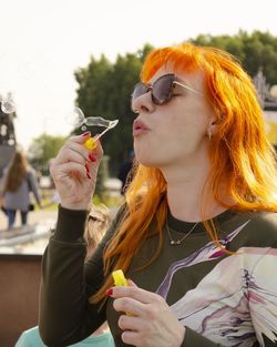 Close-up of woman blowing bubbles outdoors