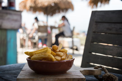 Close-up of prepared potatoes in bowl on cutting board over table at beach