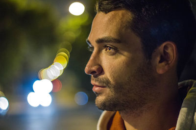 Close-up of young man looking away at night