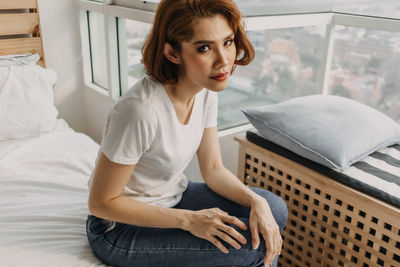 Young woman sitting on bed at home