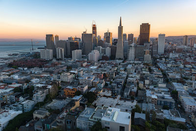 Modern buildings in city against sky during sunset