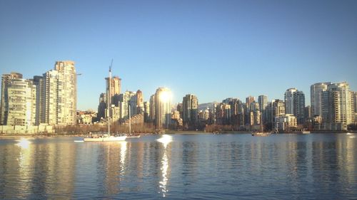 Modern buildings by sea against clear sky