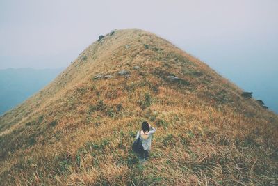 High angle view of woman standing on mountain against sky during foggy weather