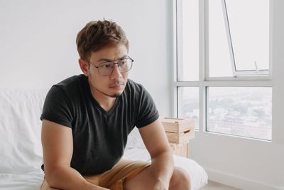 Side view of young man sitting at home