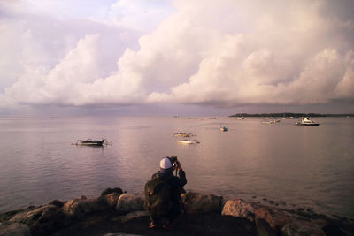 Rear view of man standing at beach against sky