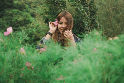 Portrait of woman wearing flower while standing amidst plants