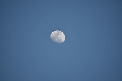 Low angle view of moon against clear blue sky