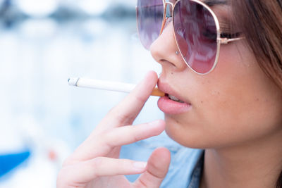 Close-up of woman in sunglasses smoking cigarette