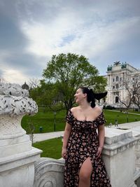 Portrait of young woman standing against built structures