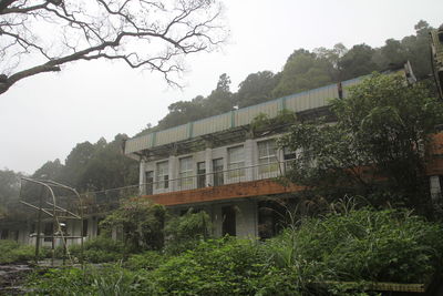 Abandoned building by trees against clear sky