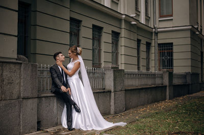 Newlywed couple romancing against building