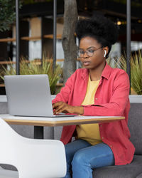 Young woman using laptop while sitting at cafe