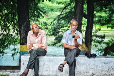 Full length portrait of a smiling young man sitting outdoors