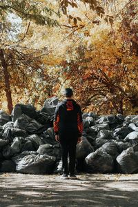 Rear view of man standing against garbage bags at park during autumn