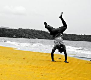 Full length of man sitting at beach against sky