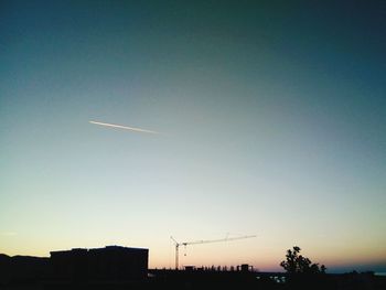 Silhouette vapor trail against clear sky during sunset