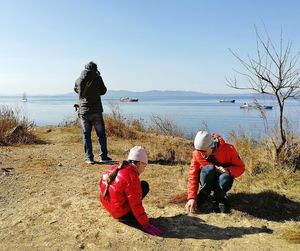 Rear view of people on shore against sky