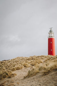 Lighthouse on beach against sky