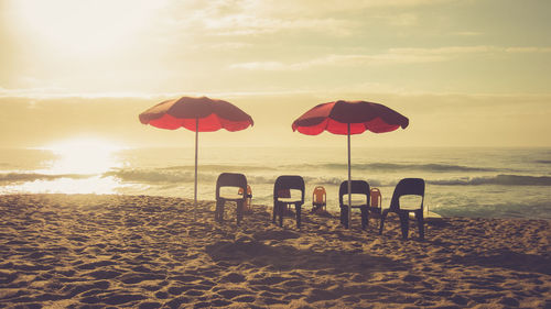 Umbrellas on beach against sky during sunset