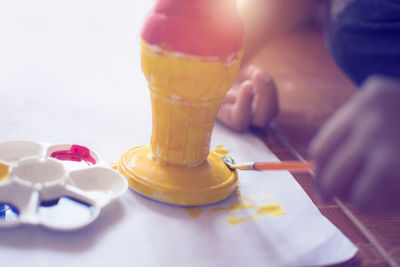 Close-up of hand holding ice cream on table