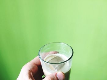 Close-up of hand holding drink against white background